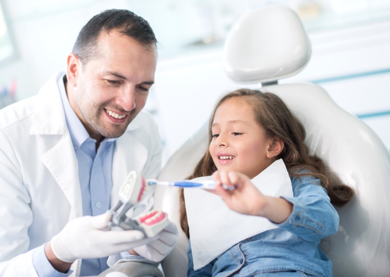 Pediatric dentist demonstrating the right way to brush teeth for healthy gums in Tempe, AZ