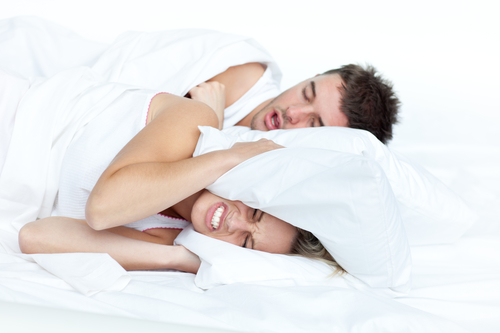 Couple in bed while the woman is trying to sleep and the man is snoring