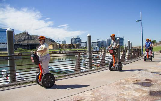 Segway's parked along the scenic river walk, surrounded by lush greenery in Tempe, AZ