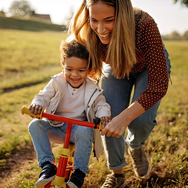 mother teaching son to ride tricycle